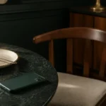 Teléfono boca abajo sobre una mesa, al lado de una silla vacía y un plato sin recoger.