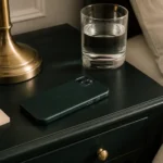 Celular boca abajo sobre una mesa de noche, lámpara apagada y un vaso de agua