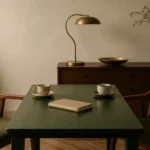 Dos sillas frente a una mesa con un cuaderno cerrado y dos tazas, sin nadie sentado.