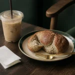 Taza de café frío y un recibo doblado junto a un plato con pan